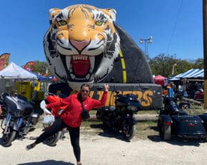 A motorcycle enthusiast poses with the Law Tigers inflatable during Rumble on the River in Bandera, TX