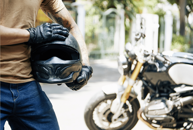man holding a motorcycle helmet standing next to his bike